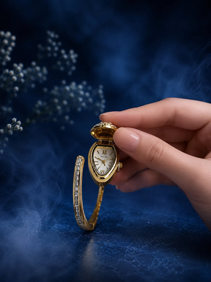 Bracelet Watch with gold-toned bangle, hidden analog dial, crystal-studded cover, and clear stone detailing