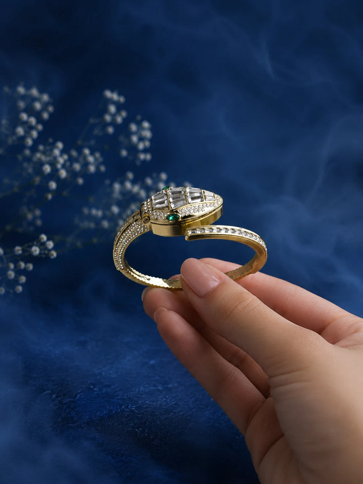 Bracelet Watch with gold-toned bangle, hidden analog dial, crystal-studded cover, and clear stone detailing